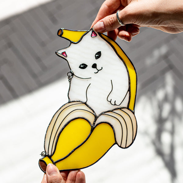 Hand holding a cartoon dog inside a banana with a blurred outdoor background