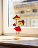 Decorative stained glass mushroom sculpture on a windowsill with a blurred building exterior.