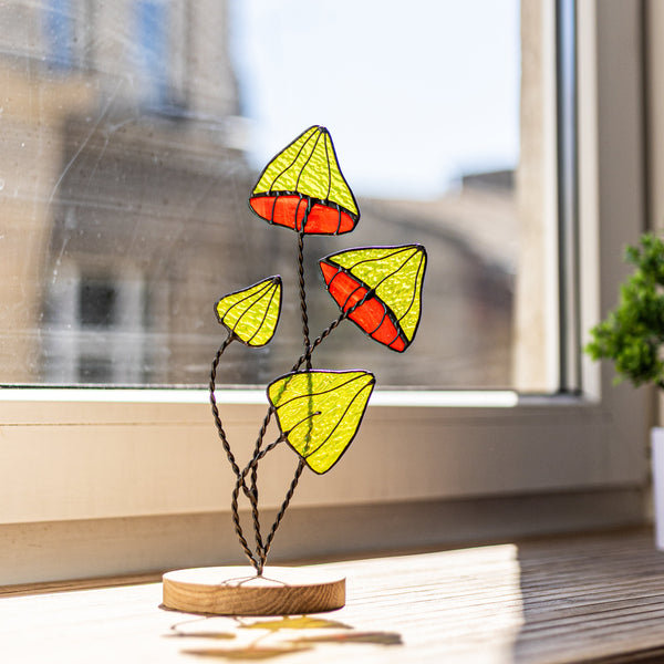 Decorative stained glass piece on a windowsill with a blurred building exterior in the background.