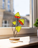Decorative stained glass piece on a windowsill with a blurred building exterior in the background.