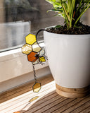 Potted plant on a windowsill with a stained glass sun catcher.