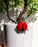 Red ladybug ornament on a white pot with a plant in the background
