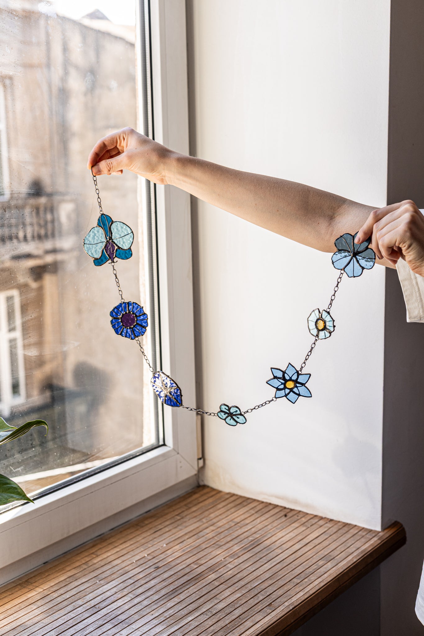 Person holding a floral necklace by a window