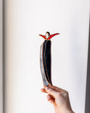 Hand holding a unique, abstract sculpture against a plain background