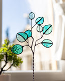 Stained glass window hanging with leaf design in a blurred indoor setting