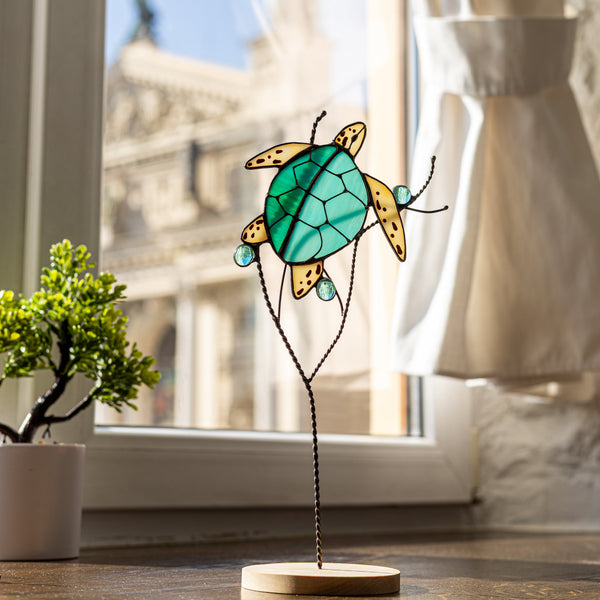 Ocean-inspired stained glass turtle with turquoise shell and white fins, displayed on a wooden base with copper stem – perfect for pot, vase, or shelf decor