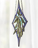 A stained glass suncatcher featuring a hanging olive branch with green leaves, set against a blue and purple diamond-shaped border with iridescent white glass panels, suspended by a metal chain.