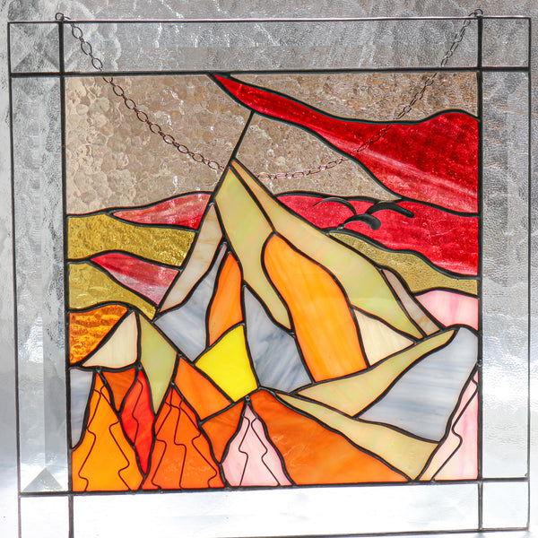 Stained glass panel with abstract mountain design in a home setting