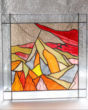 Stained glass panel with abstract mountain design in a home setting