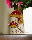 Decorative mushroom ornament with red caps and white spots on a wooden surface.