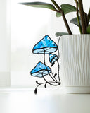 Blue stained glass mushroom decoration next to a white pot with green plants