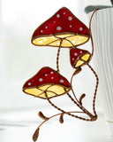 Decorative mushroom-shaped lamp with red caps and white spots on a white background