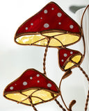 Decorative stained glass wall art of red mushrooms with white spots on a white background