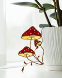 Decorative stained glass mushroom lamp next to a white vase with green leaves.