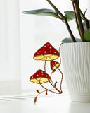 Decorative stained glass mushrooms with white polka dots on a white surface.