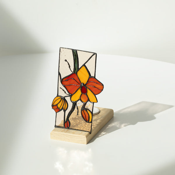 Stained glass butterfly sculpture on a wooden base against a white background