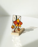 Stained glass butterfly sculpture on a wooden base against a white background