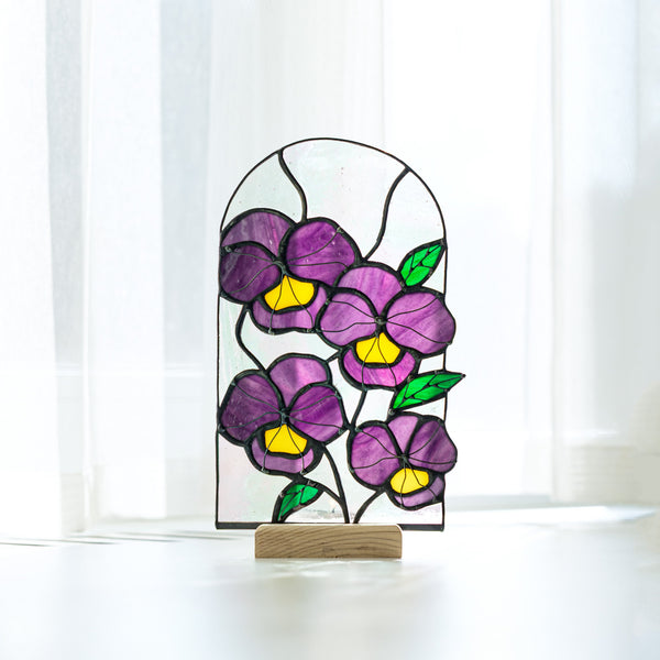 Stained glass panel with purple flowers on a white surface