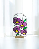 Stained glass panel with purple flowers on a white surface