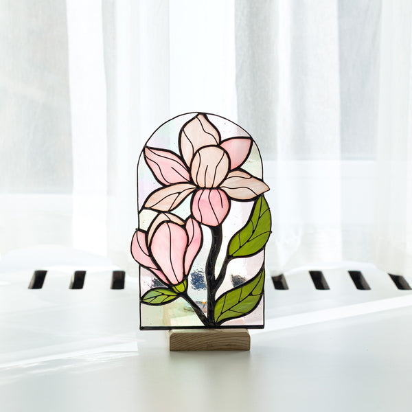 Stained glass flower panel on a stand with white curtains in the background