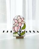Stained glass flower panel on a stand with white curtains in the background