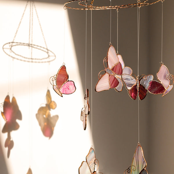 Butterfly stained glass suncatcher in soft pink with floral accents, handmade from high-quality glass, perfect for windows, walls, and as a gift for nature lovers.