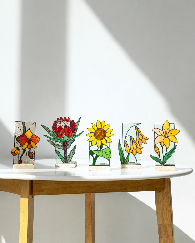 Set of five stained glass panels with floral designs on a wooden table.