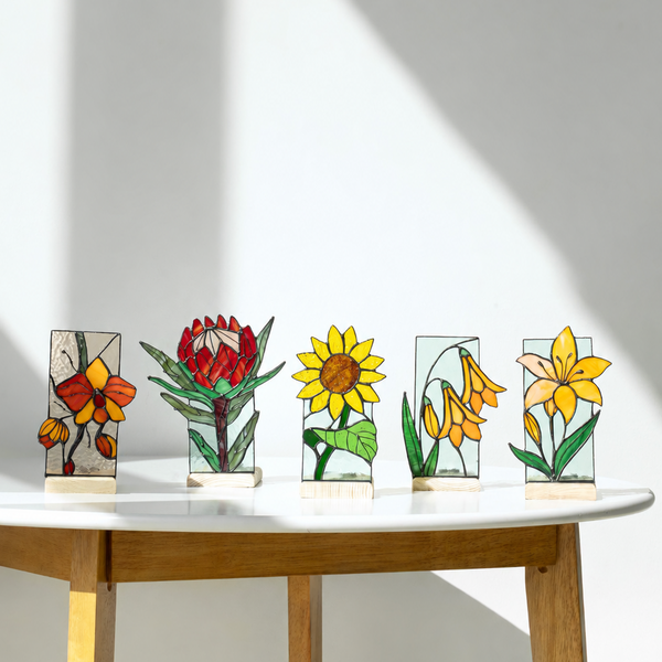 Set of five stained glass panels with floral designs on a wooden table.