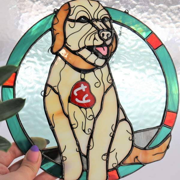 Stained glass-style dog window cling held by a hand with a plant in the background