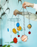 Colorful hanging mobile with celestial designs against a light blue background