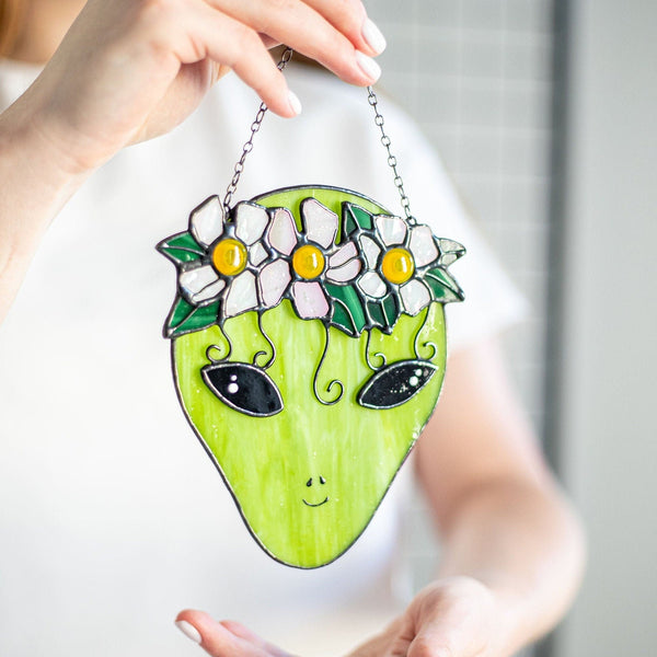 Person holding a green alien-shaped bag with floral design