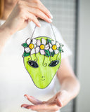 Person holding a green alien-shaped bag with floral design