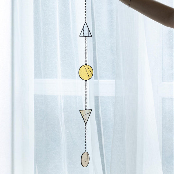 Decorative hanging with geometric shapes against a light curtain background