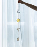 Decorative hanging with geometric shapes against a light curtain background